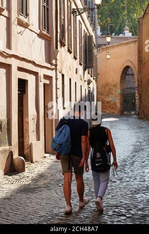 Couple Seen From Behind Walking Along an Ancient Street in Central Rome. Pavement Made of Cubic Bricks, Typical of Rome (Sampietrini)
