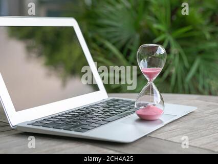 Hourglass on laptop computer. Time management, countdown and deadlines concept. Stock Photo