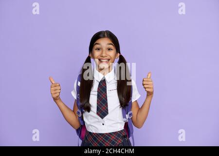 Excited happy indian school girl show thumbs up isolated on violet background. Stock Photo