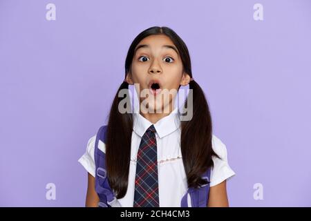 Funny amazed indian school girl looking at camera isolated on violet background. Stock Photo