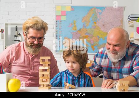 Grandfather father and cute little son having fun at home. Men family. Grangfather, Father and son playing jenga game at home. Stock Photo