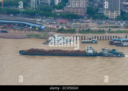 Barge full of logs crusing along a river in China Stock Photo