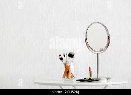 Set of makeup cosmetics with brushes and mirror on table Stock Photo