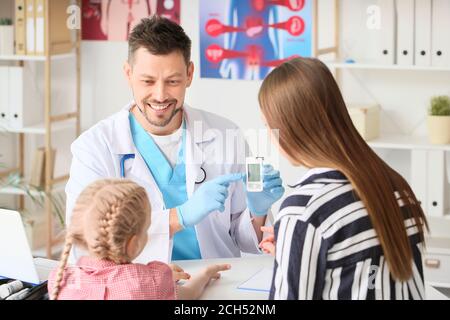 Doctor measuring blood sugar level of little girl in clinic Stock Photo