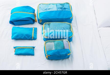 Set of travel organizers with belongings on bed at home Stock Photo