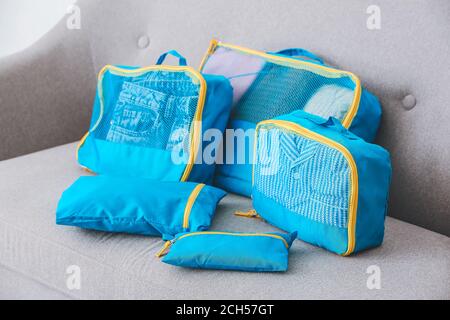 Set of travel organizers with belongings on sofa at home Stock Photo