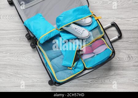 Suitcase and set of travel organizers with belongings on floor Stock Photo