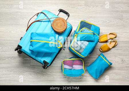 Suitcase and set of travel organizers with belongings on floor Stock Photo