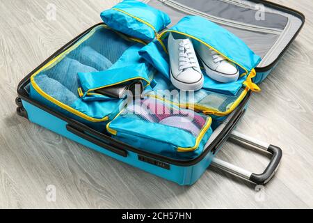 Suitcase and set of travel organizers with belongings on floor Stock Photo