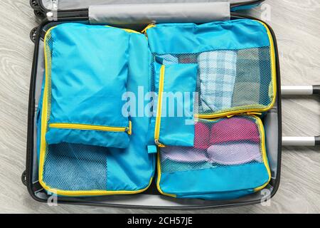 Suitcase and set of travel organizers with belongings on floor Stock Photo