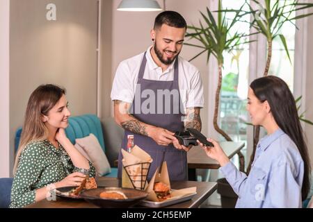 Woman paying bill in restaurant through terminal Stock Photo