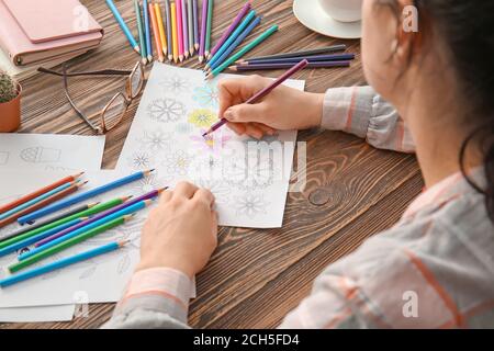 Woman coloring picture at table Stock Photo