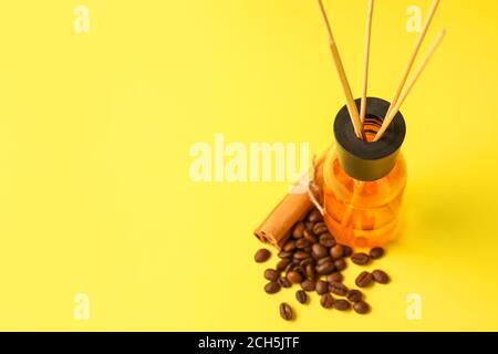 Reed diffuser with coffee beans and cinnamon on color background Stock Photo