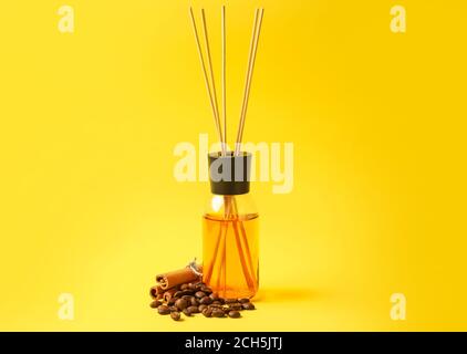 Reed diffuser with coffee beans and cinnamon on color background Stock Photo