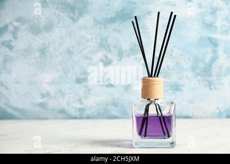 Reed diffuser on table against color background Stock Photo