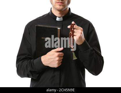 Handsome priest with Bible and rosary beads on white background Stock Photo