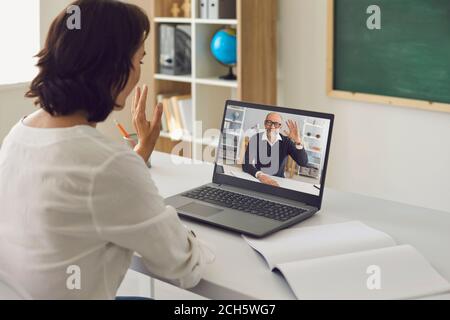 Education training teaching online. Female teacher greets senior male university student using laptop video call online. Stock Photo