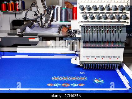 A modern professional embroidery machine for embroidery on various fabrics makes patterns with multi-colored spools of thread, space for text. Stock Photo