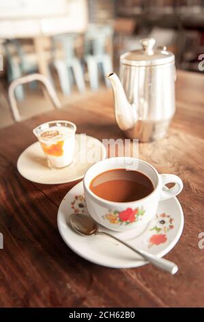 Relaxing in an old coffee shop in early morning, vintage a cup of coffee with soft boiled egg and tea kettle are on old wooden table. Stock Photo