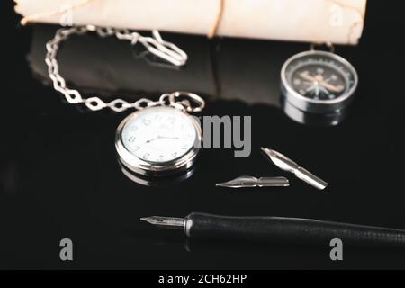 Fountain pen with pocket clock on dark background Stock Photo
