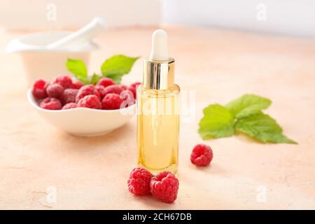 Bottle of raspberry essential oil on color background Stock Photo