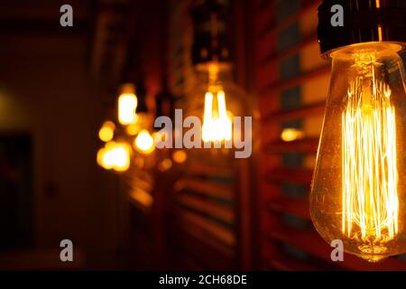 Golden shining antique Edison style bulbs in the dark. Lighting decor concept. Vintage light bulbs. Blur background of retro lights Stock Photo