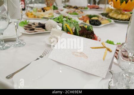 Blank guest card with wedding rings on restaurant table with selective focus Stock Photo