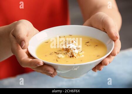 Woman with tasty popcorn soup in bowl, closeup