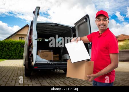 Delivery Man Showing clipboard Holding Box Watching in Camera. Indian Delivery Boy Clipboard Signature at Delivery Point Stock Photo
