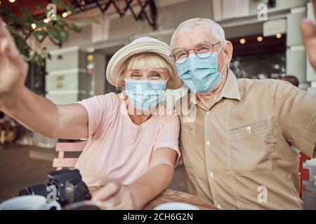 Elderly couple in protective masks sitting in a cafe Stock Photo
