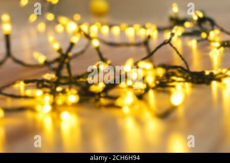 Garland glowing with warm light on floor. The atmosphere of the Christmas holidays. Overlay with golden bokeh. Stock Photo