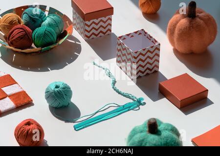 Creative geometric arrangement of craft materials for knitting and crochet with long shadows. Various yarn balls, crochet hook with thread. Decorative Stock Photo