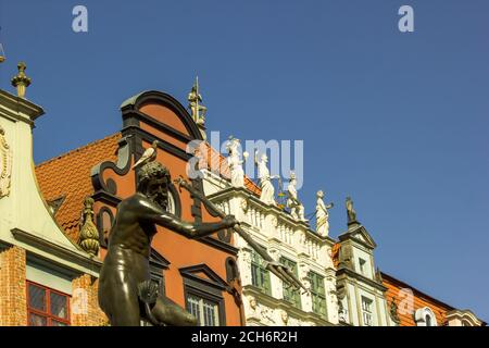 Gdansk, North Poland - August 14, 2020: Close up of a famous neptune's fountain against famous white building with golden statues on top situated in t Stock Photo