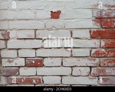 The texture of red brickwork, painted with white paint, which eventually fell apart. Stock Photo