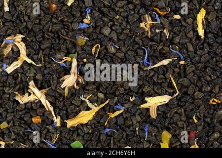Black tea mixed with herbs and dry fruits. Calendula, sunflower, cornflower, rosehip berries. texture. Stock Photo