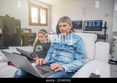 Man working at home beside his daughter. Smart working in covid-19 time. Stock Photo