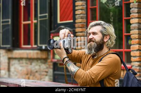 Modern business. Journalist reporter. Brutal stylish man with retro camera. Old technology. Professional photographer use vintage camera. Photography business. Bearded man hipster take photo. Stock Photo