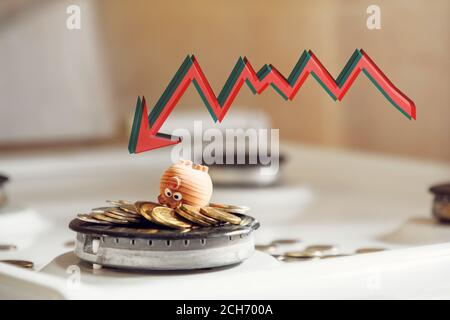 the concept of bankruptcy or increasing public services. red arrow over a small toy in the form of a pig on coins and a gas stove. Stock Photo