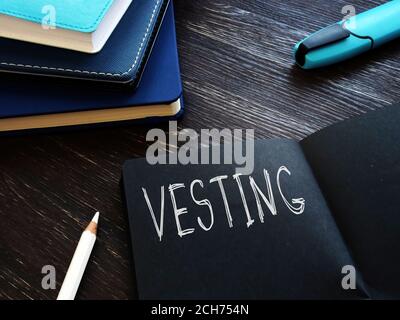 Vesting handwritten lettering in the black notebook. Stock Photo