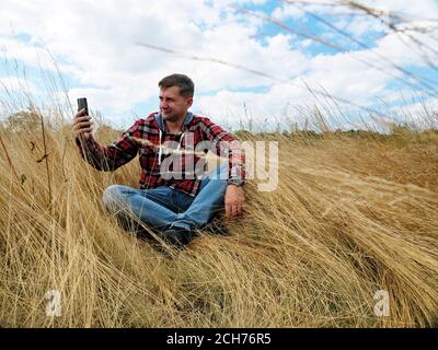 A man in the autumn nature takes a selfie and uses a smartphone. Stock Photo