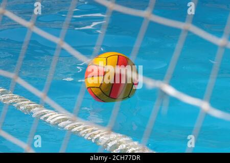 Colored water polo ball floating on blue swimming pool water with selective focus Stock Photo