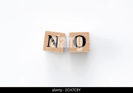 A wooden block with the word NO written on it on a white background Stock Photo