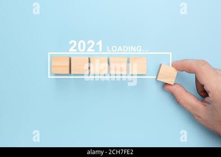 Loading new year 2021 with hand putting wood cube in progress bar. creative background for the new year. Loading new year 2021 concept Stock Photo