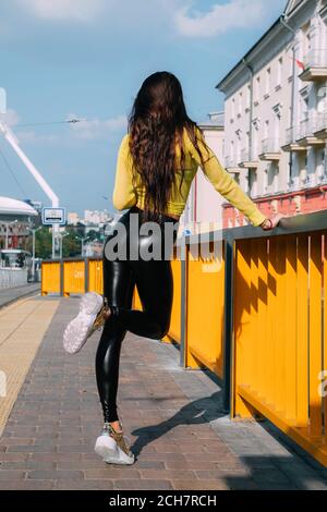 Pretty girl with long dark hair wearing a bright yellow sweater shiny