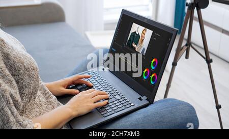 Woman editing video on laptop computer for her vlog. Woman working on laptop at home