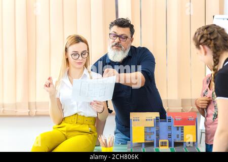 Multiethnic architects working on blueprint construction mockup with team Stock Photo