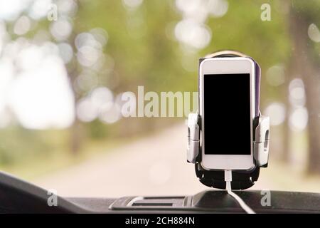 Mobile phone with GPS card in the car. A white smartphone on a stand in the car is used for navigation. Stock Photo