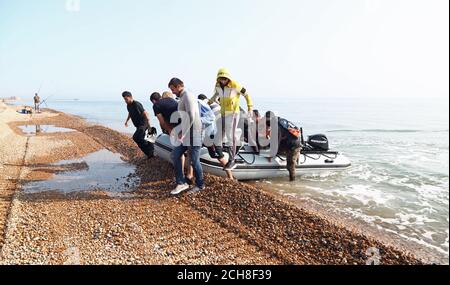 A group of people thought to be migrants arrive in an inflatable boat at Kingsdown beach, near Dover, Kent, after crossing the English Channel. Stock Photo