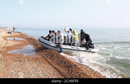 A group of people thought to be migrants arrive in an inflatable boat at Kingsdown beach, near Dover, Kent, after crossing the English Channel. Stock Photo