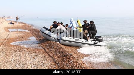 A group of people thought to be migrants arrive in an inflatable boat at Kingsdown beach, near Dover, Kent, after crossing the English Channel. Stock Photo